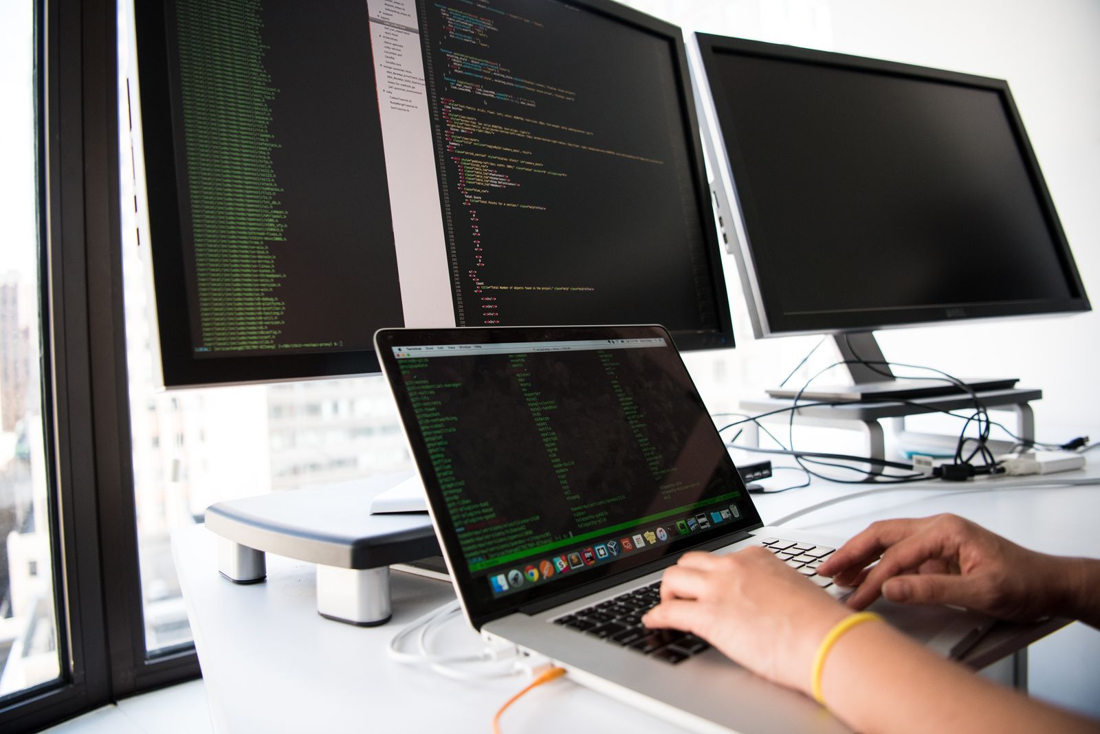 Engineer working across a laptop and dual monitors
